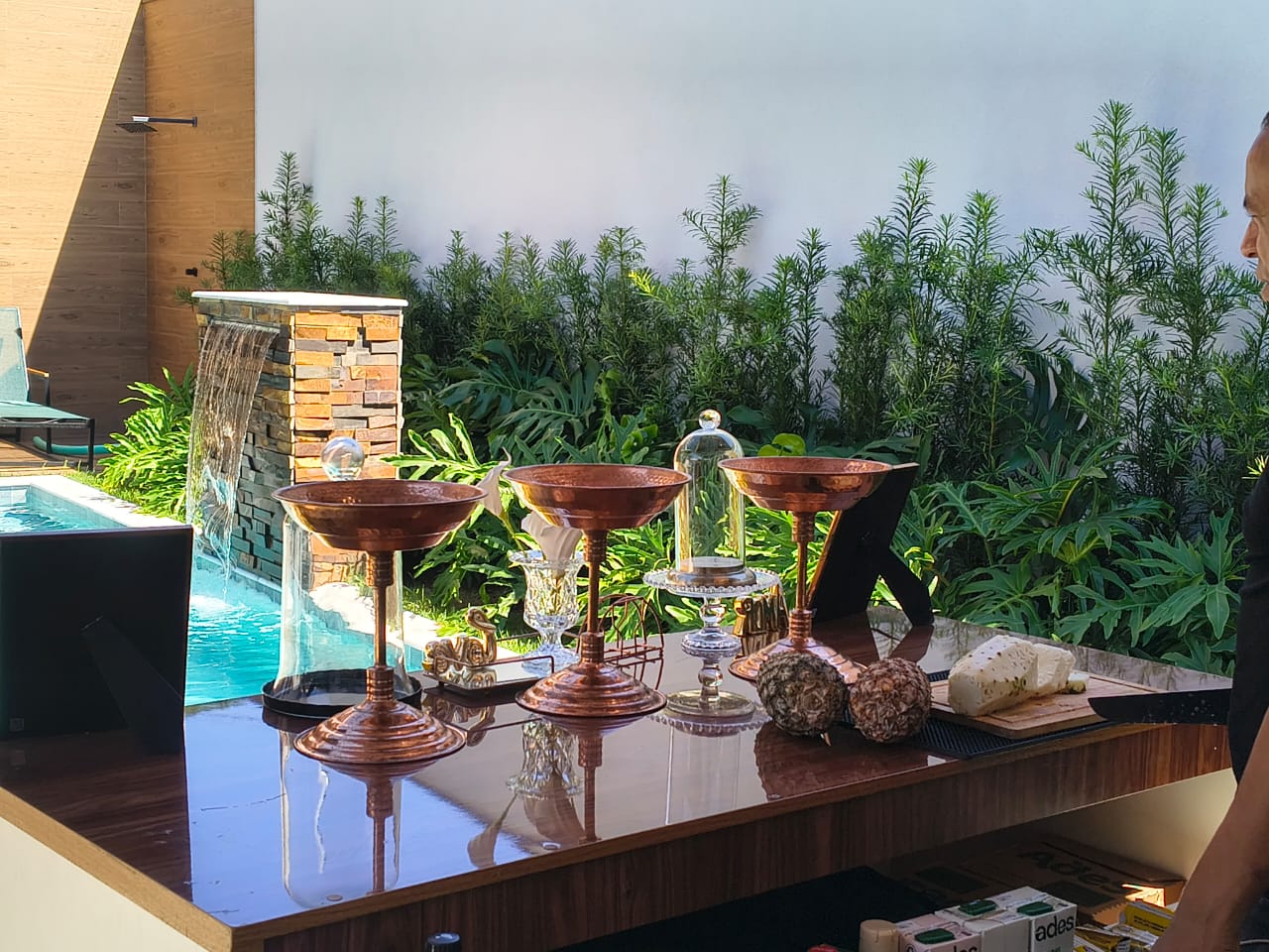 Bar externo montado à beira da piscina com bowls de cobre e comida fresca
