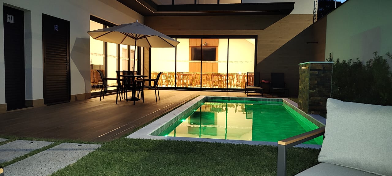 Piscina iluminada em frente ao salão envidraçado