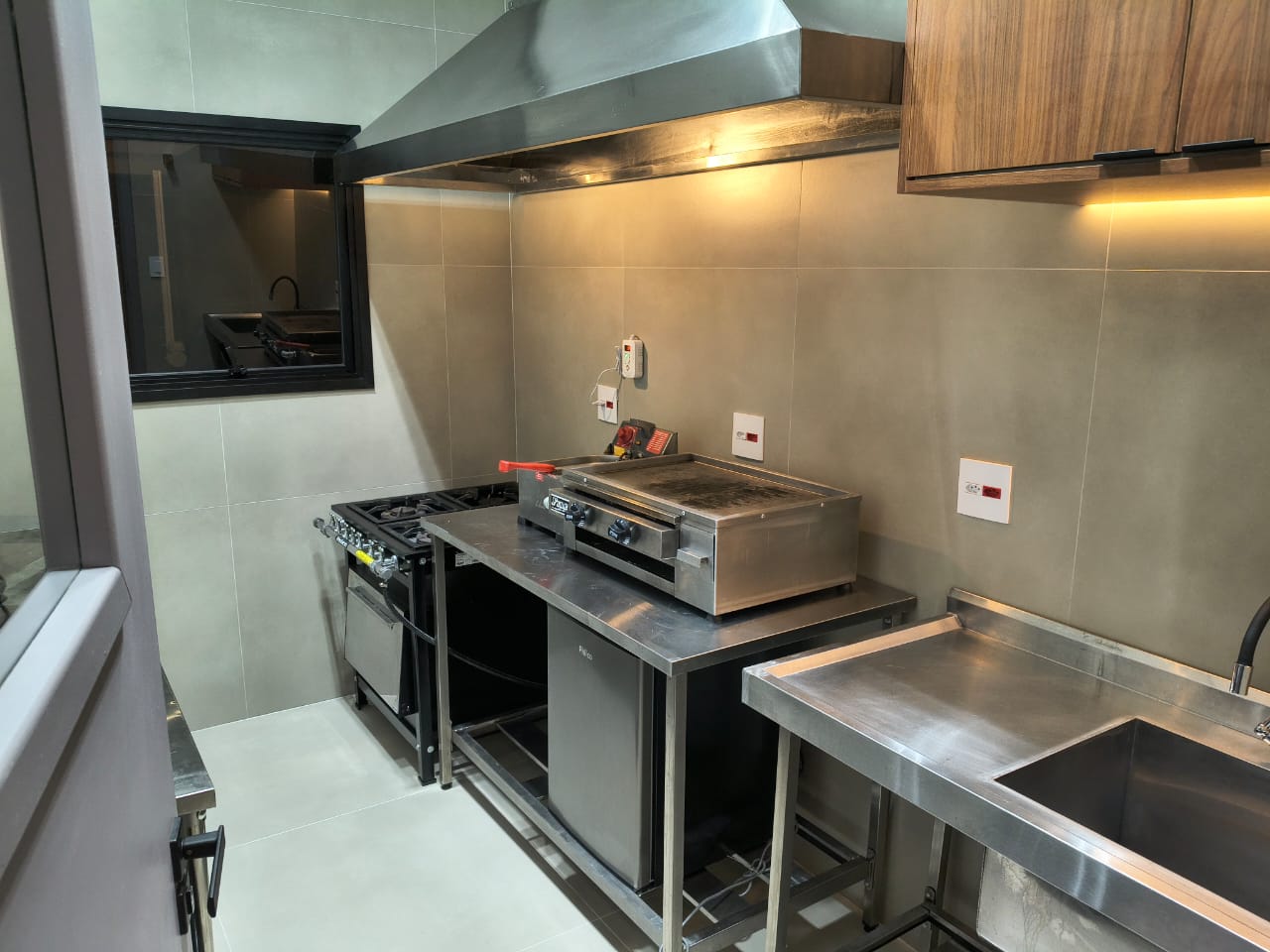 Cozinha industrial equipada com fogão, chapa e bancadas em inox